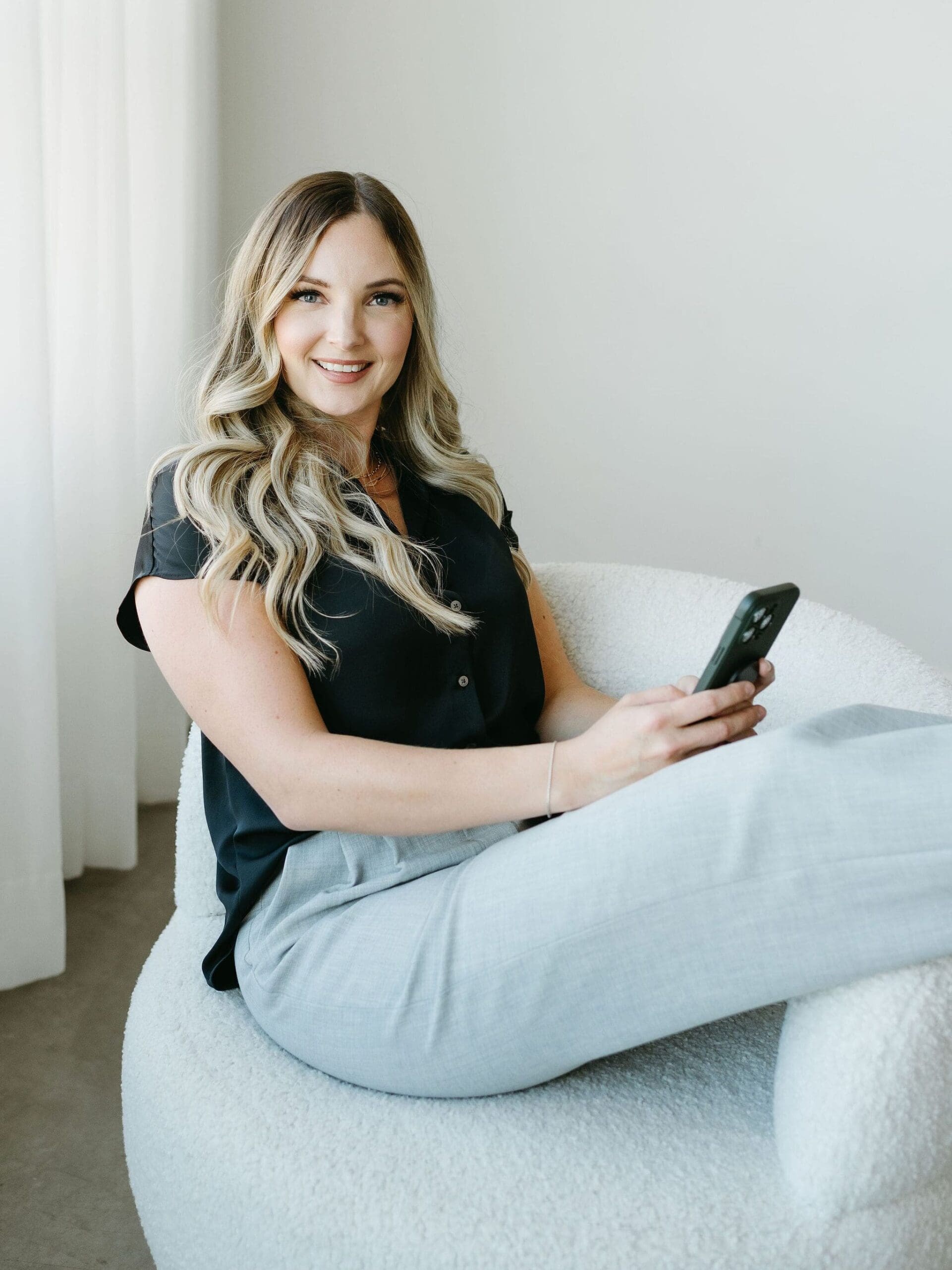 Karly Whitaker sits in office chair as she talks on phone about how a great client experience always sells. 