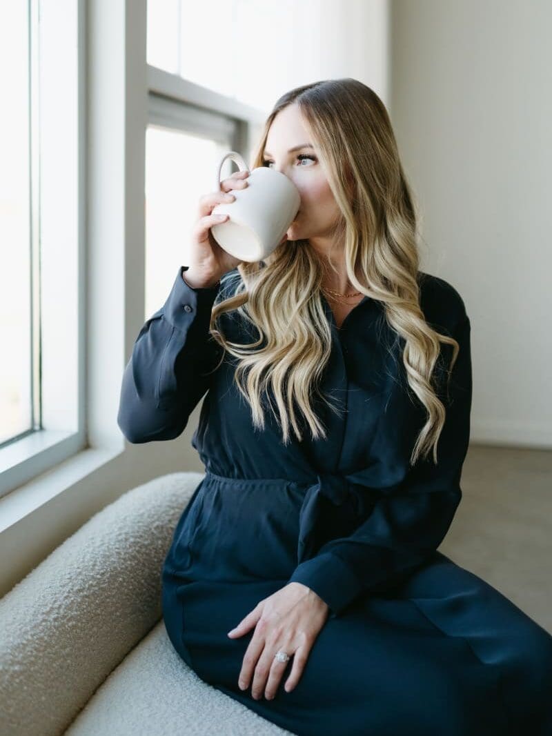 Woman sipping coffee while sitting by a window.