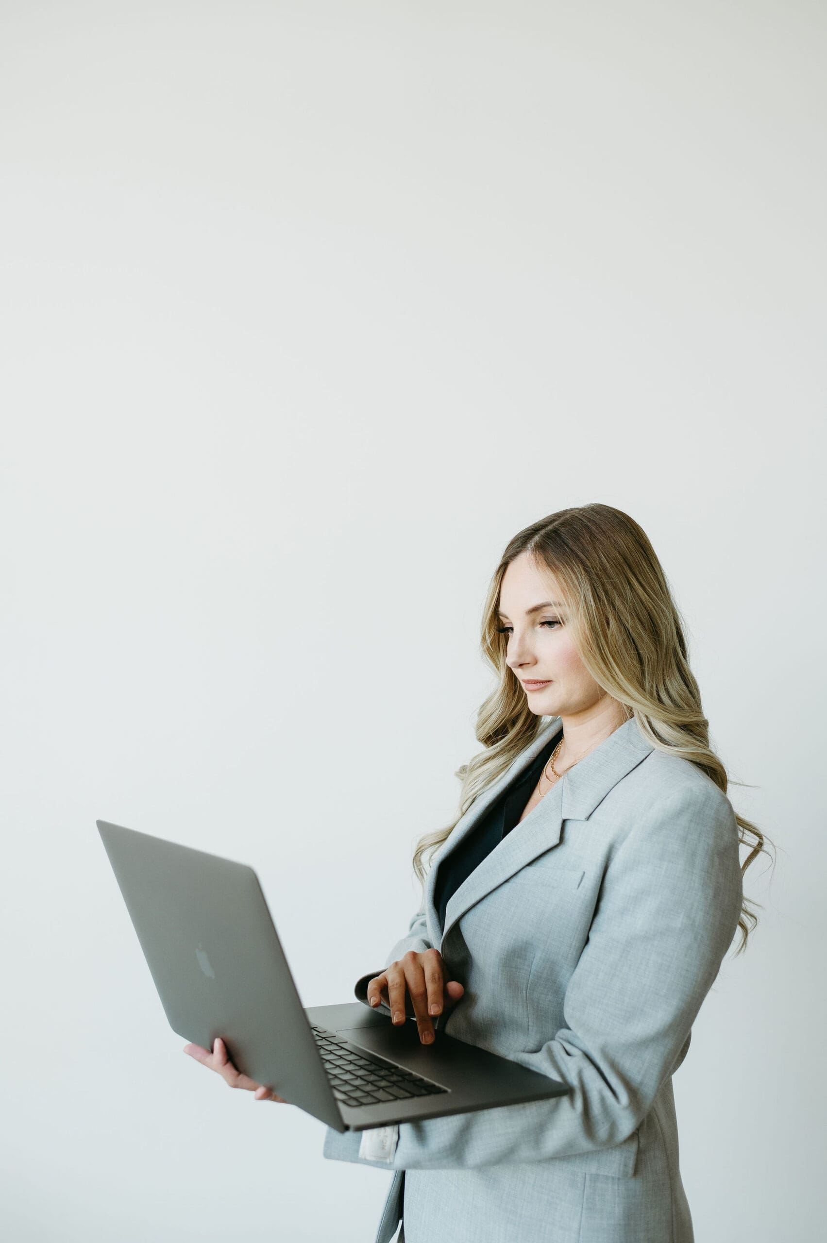 Business consultant working on a laptop in a clean, bright studio space, representing HoneyBook lead forms, client workflows, and streamlined backend systems.