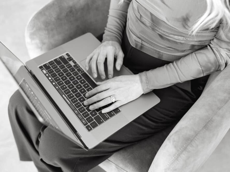 Close-up of hands typing on a laptop, representing building systems, workflows, and client onboarding automation inside a CRM for service providers.