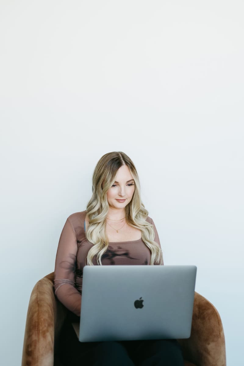 Business owner working from her laptop in a bright office, using the HoneyBook scheduler to automate client bookings and manage her schedule more efficiently.