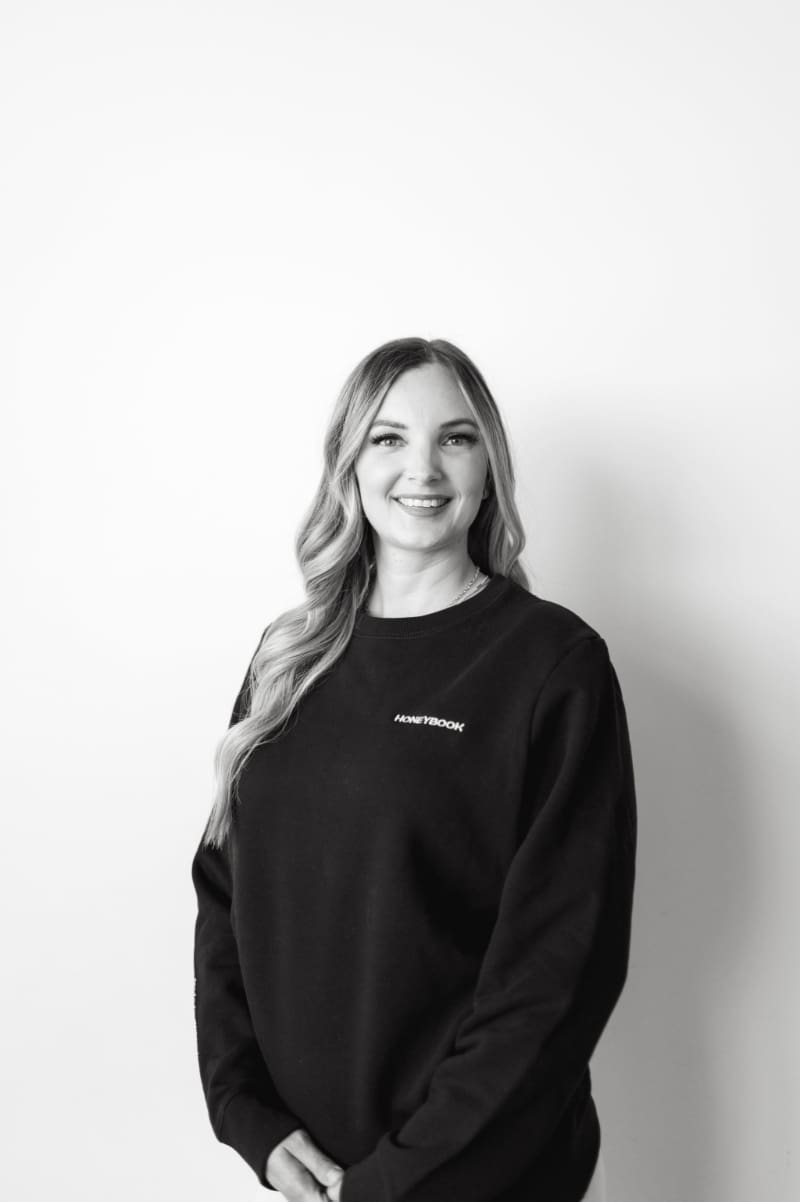 HoneyBook Pro Karly whitaker smiling in a HoneyBook sweatshirt, sharing her expertise on creating HoneyBook email templates that save time and sound personal.